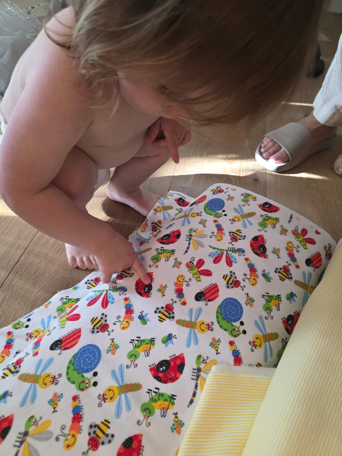 Toddler pointing to ladybug on bolt of fabric